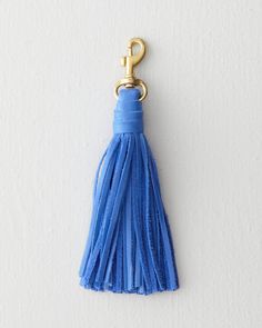 a blue tasseled keychain hanging from a hook on a white wall