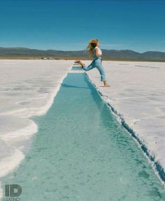 a woman jumping in the air over a pool of water on top of snow covered ground