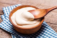 a wooden spoon filled with cream on top of a blue and white checkered napkin