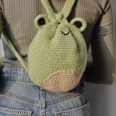 a crocheted animal purse is held by a woman's back with her hands in her pockets