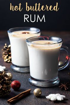 two glasses filled with hot buttered rum on top of a table next to christmas decorations