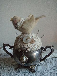 there is a silver tea pot with buttons on it and two birds sitting on top