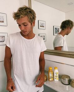 a man standing in front of a bathroom mirror with his hands on his hips and looking at his cell phone