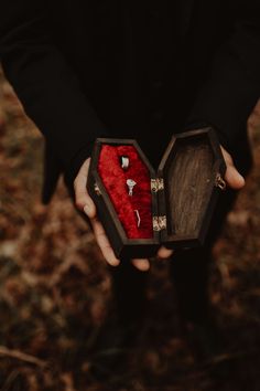 a person holding an open wooden box with jewelry in it's hands and the lid opened