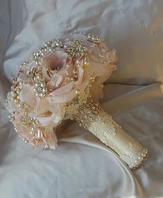 a bridal bouquet with pearls and flowers on a white satin bed sheet in the sunlight