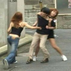 three young women are walking down the street with their arms around each other and one woman is holding her head