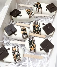 six decorated popsicles in a white box with brown and gold decorations on them,