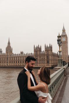 a man and woman standing next to each other in front of the big ben clock tower