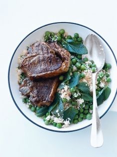 a white plate topped with meat and peas next to a bowl of rice covered in greens