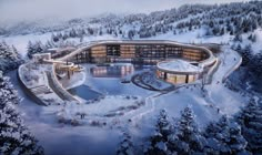 an aerial view of a building surrounded by snow covered trees and evergreens in the background