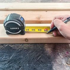 a person measuring with a tape measure on a piece of wood next to a ruler