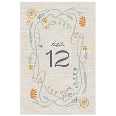 a table number card with an orange and blue floral design on the front, surrounded by leaves and flowers