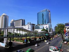 a city street filled with lots of traffic and tall buildings in the background on a sunny day