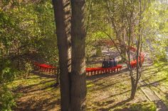 two people sitting on a red bench in the middle of a wooded area with trees