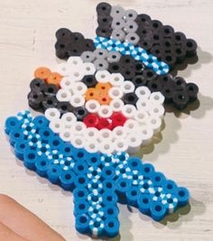 a hand holding a beaded snowman ornament on top of a table