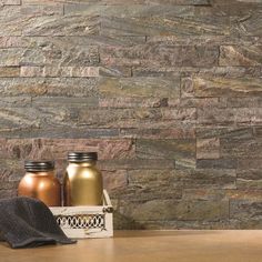 two jars sitting next to each other on top of a wooden table in front of a stone wall