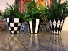 three black and white planters sitting on top of a counter