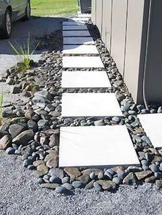 a car parked next to a building with rocks on the ground and gravel around it