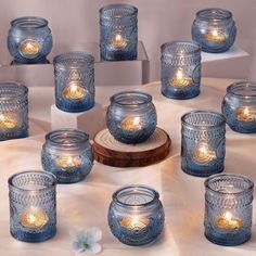 many blue glass jars with lit candles in them