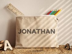 a pencil case sitting on top of a table next to a ruler and wooden letters