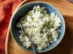 rice in a blue bowl with a spoon on a wooden serving tray next to an orange towel