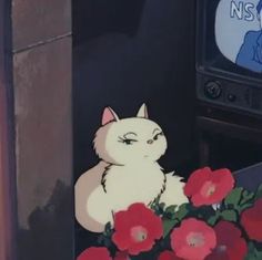 a white cat sitting in front of a flower pot with red flowers next to it