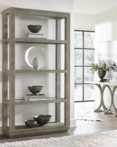 a wooden shelf with bowls and plates on it in a room next to a white rug