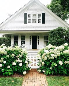 a white house with black shutters and hydrangeas on the front door is featured in instagram