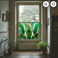 a green stained glass window sitting next to a potted plant on top of a wooden floor