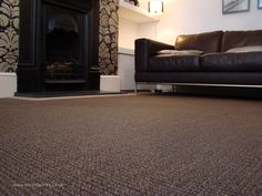 a living room with a couch, fireplace and carpeted floor in front of it