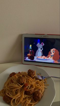 a white plate topped with spaghetti and meat next to a cell phone on top of a table