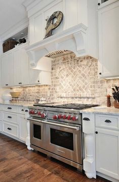 a kitchen with white cabinets and stainless steel stove top oven in the center of the room