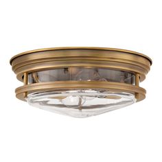 a flush light fixture with clear glass in an antique brass finish, on a white background