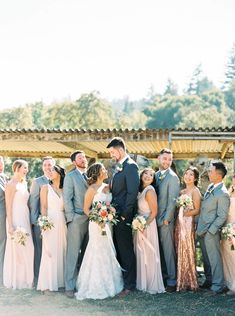 a group of people standing next to each other in front of a wooden structure and trees