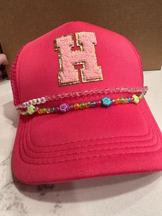 Hat with personalized jewelry chain attached. Add a name, a sports team, a vacation spot, the possibilities are endless! Adjustable Pink Baseball Cap, Trendy Snapback Hat For Sports Events, Trendy Adjustable Snapback Hat For Sports Events, Adjustable Beach Baseball Cap, Customizable Trucker Hat With Visor, Trendy Customizable Adjustable Baseball Cap, Personalized Adjustable Baseball Cap For Summer, Trendy Adjustable Beaded Hats, Adjustable Pink Trucker Hat For Sports Events