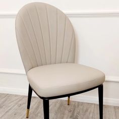 a beige chair sitting on top of a hard wood floor next to a white wall