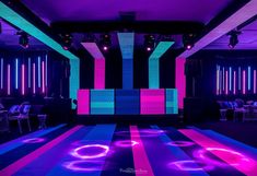 a dance floor is lit up with neon lights in the middle of an empty room