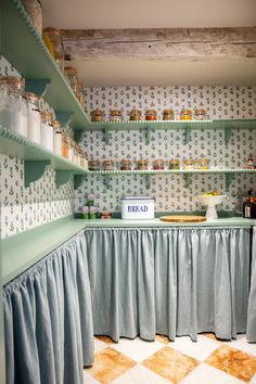 a kitchen with blue and white wallpaper, shelves filled with jars and containers on top of them