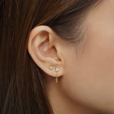 a woman wearing a pair of ear piercings with pearls on the end of her ears