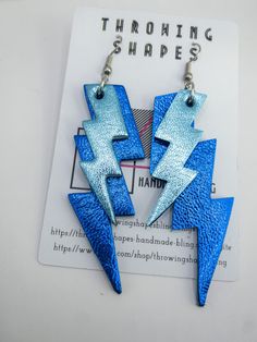 Striking lightening strikes! Layered lightening bolts made with vibrant blues metallic leather. Lightweight statement earrings.  All my leather earrings are made using leather offcuts and repurposed leathers. My aim is to create fun and more sustainable jewellery. Finding: gold plated hooks  Drop: 7cm approx Creative Costume, Bolt Earrings, 80s Earrings, Creative Costumes, Crochet Inspo, Sustainable Jewelry, Metallic Leather, Leather Earrings, Costume Ideas