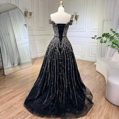 a black and silver dress on display in front of a white chair with a mirror behind it