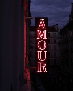 a red neon sign that reads amour on the side of a building at night