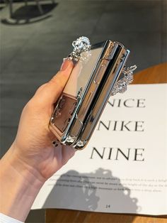 a person holding up a cell phone case with diamonds on the front and bottom side