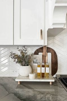 a kitchen with white cabinets and marble counter tops, including soap dispensers