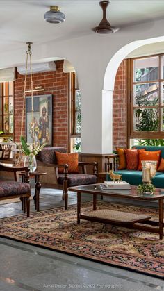 a living room filled with lots of furniture next to a brick wall covered in windows