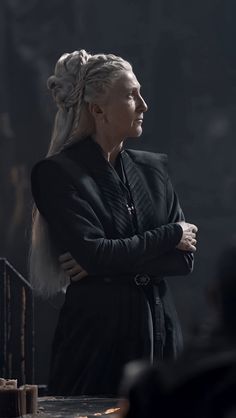 the game of thrones character is standing with her arms crossed and looking off to the side