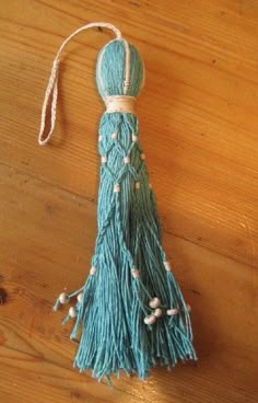 a tasseled ornament hanging on a wooden table with string and beads