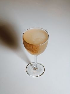 a glass filled with liquid sitting on top of a white table next to a brown object