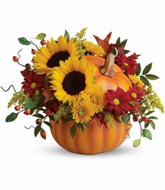 a pumpkin filled with sunflowers and other flowers