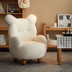 a white teddy bear chair sitting on top of a wooden floor next to a table